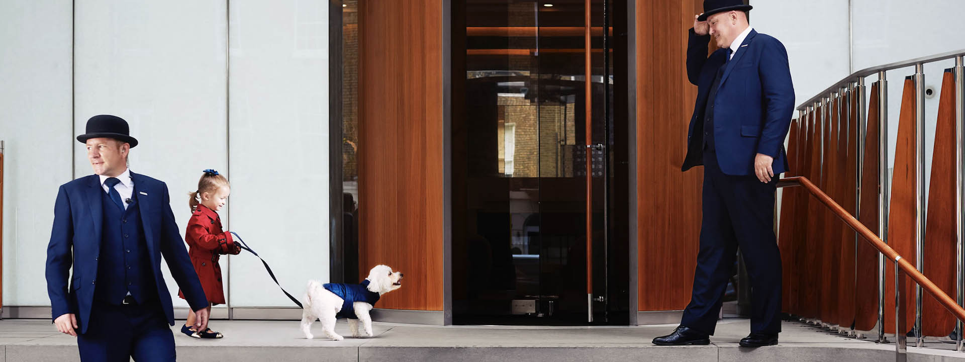 A doorman at The Berkeley greeting a child with her dog 