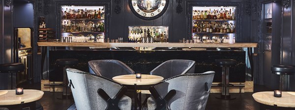 Four deep blue lounge chairs around a table in front of the bar with blue interior