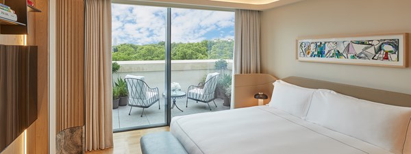 Master bedroom with floor to ceiling windows looking out to terrace and cream bedding on king size bed